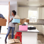 two people sharing a smile while helping each other move into a new home